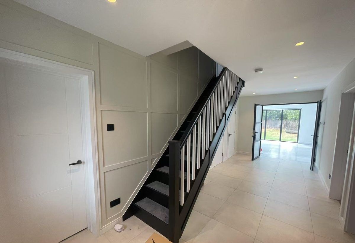 Finished hallway renovation with panelled staircase and tiled floor — TrustBuilt project